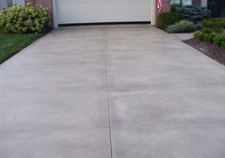 Smooth residential concrete driveway in front of a garage door.